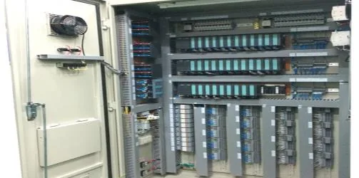 Open industrial automation cabinet with PLC modules, terminal blocks and neat cable ducting