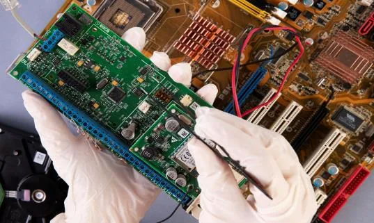 Technician inspecting a variable frequency drive circuit board during component-level repair
